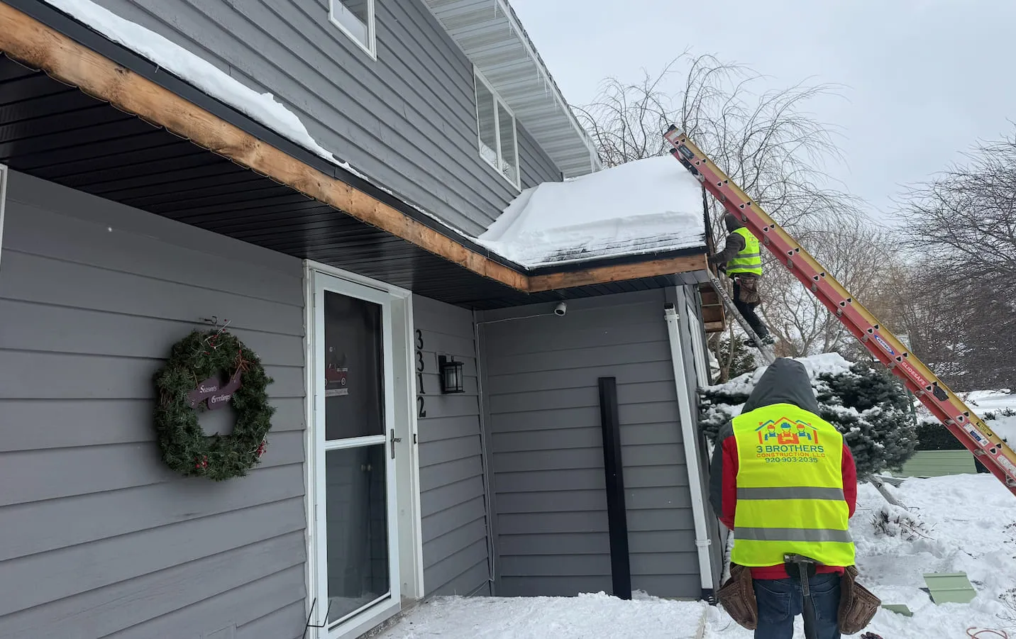 3 Brothers Construction crew clearing snow and ice from a roofline in Wisconsin
